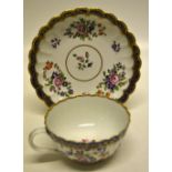 A First Period Worcester cup and saucer with panel moulded sides painted sprigs of coloured