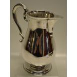 An eighteenth century Irish silver beer jug, the baluster body with a scroll spout, having a pear