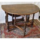 An antique oak gateleg table the oval drop leaf top, on baluster turned and block legs with