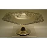 A silver cake tazza the six sided top with pierced fret panels and a serpentine edge, on a