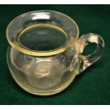 A nineteenth century infants glass sick pot, with scroll handle, 3.1in (8cm) diameter.