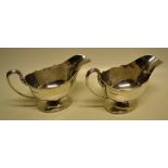 A pair of oval silver sauce boats, having a moulded rim, cast reeded capped lined scroll handles