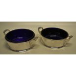A pair of silver, pail shape butter dishes with blue glass liners, having side handles. Makers