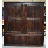 A seventeenth century oak panelled wardrobe, the pair of doors with wrought iron strap hinges. 5ft