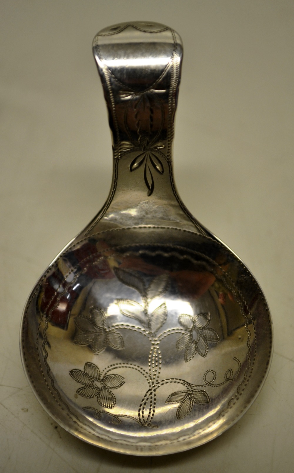 A Regency silver caddy spoon, the circular bowl engraved a flowering plant, an engraved handled.