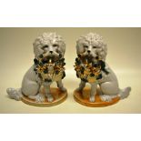 A pair of French porcelain late nineteenth century poodles, having a green ribbon to each neck and a
