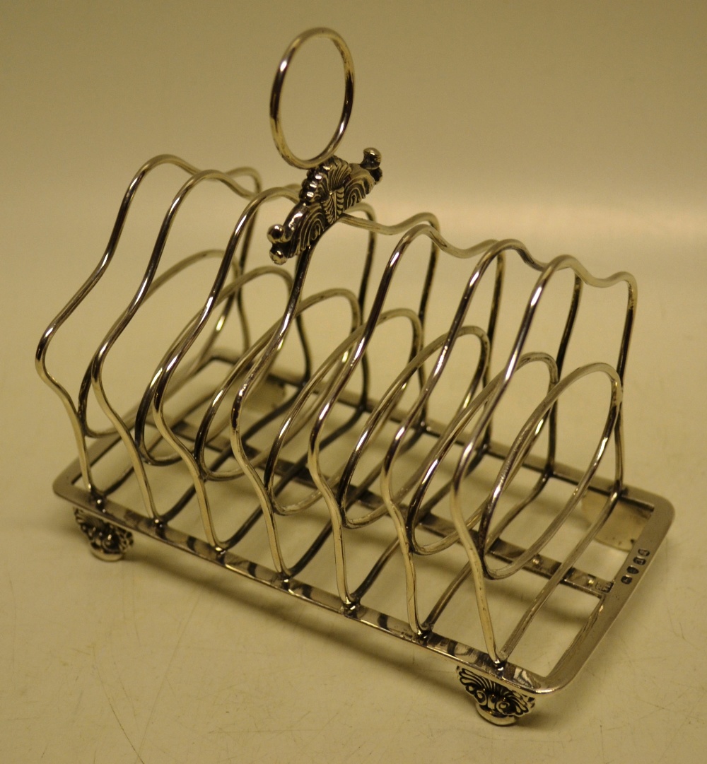 A Regency silver wirework six division toast rack, with shell and leaf scroll ring handle on shell