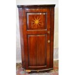 An early nineteenth century Dutch mahogany veneered standing corner cupboard, the back asymmetrical,