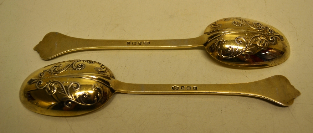 A pair of silver gilt lace back table spoons with mask foliage chased shaped terminals. Makers