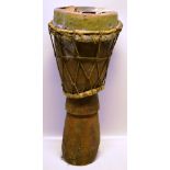 An African hardwood drum, with knee grip base, skin top damaged. 24in (61cm).