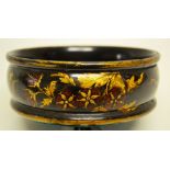 A Regency black and gold lacquer decorated papier mache coaster, decorated rose hips and foliage,