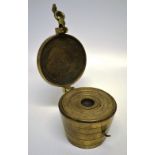 A graduated set of bronze pocket weights with a brass clasp and hinge. 3.1in (8cm) diameter.