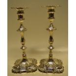 A unusual pair of early George III cast silver candlesticks, the corners with rococo shell sprays,