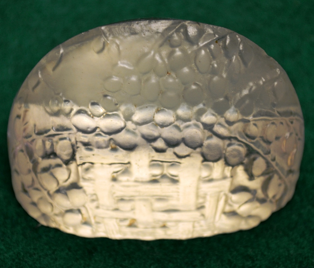 A Lalique moulded domed glass menu holder, decorated a basket of fruit, inscribed on the base R.