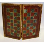 A mid nineteenth century carved red and white ivory chess set in a patterned leather bound tooled