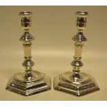 A pair of George 1st silver cast candlesticks with facetted knopped and hexagonal stems, the urn