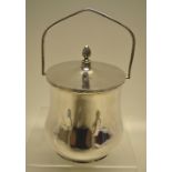 A George V silver biscuit box, the ogee body with a ribbon tied reeded rim and a swing handle, the