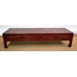 A Chinese pine opium table, painted in red lacquer, the three frieze drawers with brass handles, the