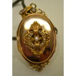 A Victorian oval polished gold locket, with a hinged cover applied a pearl and seed pearl bordered