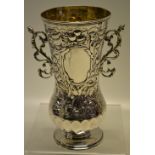 An Edwardian silver vase, the body with repousse fruit and foliage with hawks head decoration, two