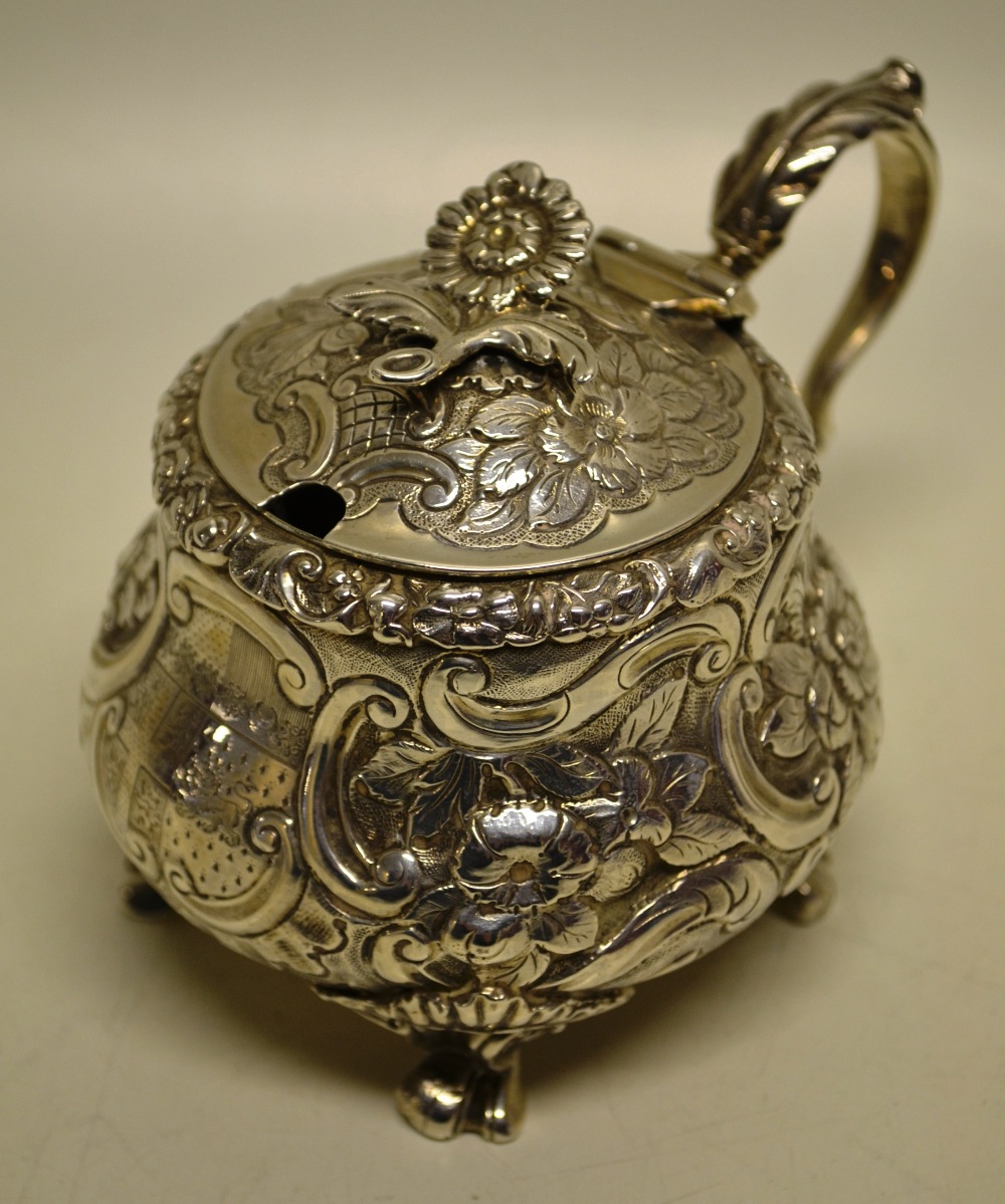 A large Regency silver mustard pot, the ogee body chased with repouse foliage scrolls and engraved