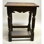 An antique oak joined stool, the plank seat with thumb out borders, the moulded scrolling frieze