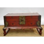 A Chinese early twentieth century chest, painted in red lacquer with brass mounts and clasp to the