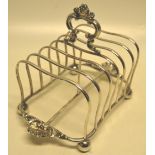 An Edwardian silver six division toast rack in the style of Paul Storr, having a cast rococo spray