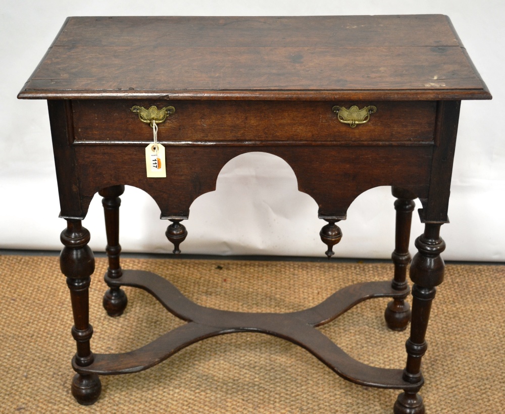 An antique oak side table, the moulded edge rectangular top above an arched frieze with a drawer