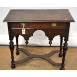An antique oak side table, the moulded edge rectangular top above an arched frieze with a drawer