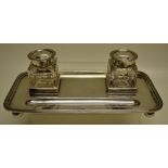 A George V silver inkstand, the rectangular tray with a pen dip and two cut glass ink bottles,