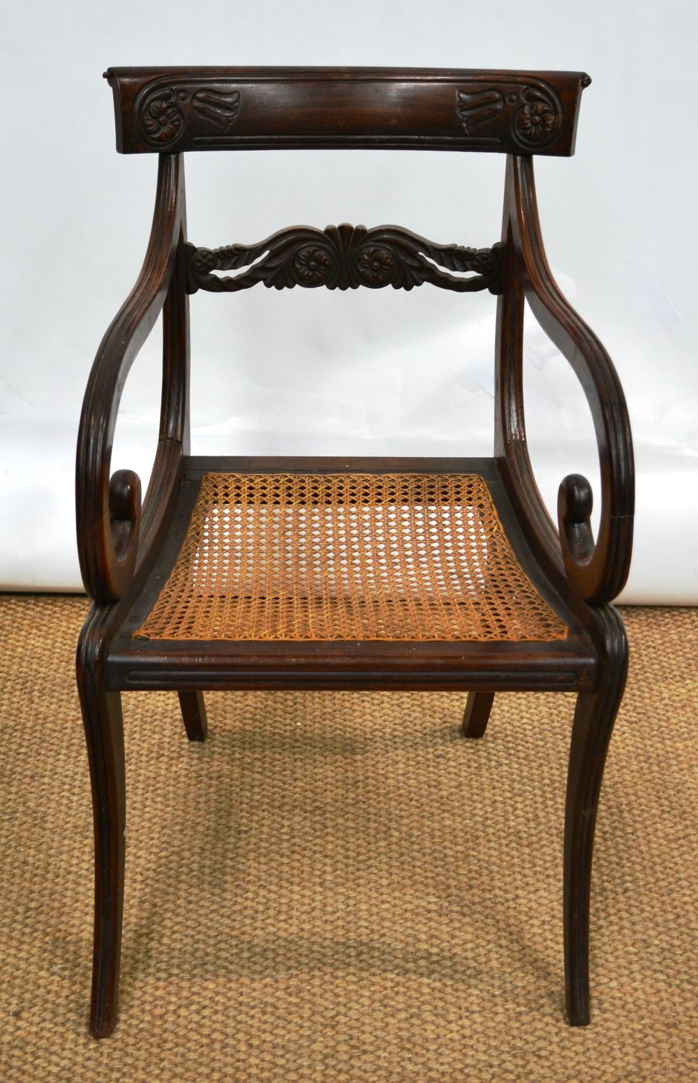 A George IV rosewood elbow chair, the back with a pierced foliage florette carved horizontal splat
