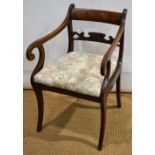 A Regency mahogany elbow chair, the back with a foliage scroll carved horizontal splat and a figured