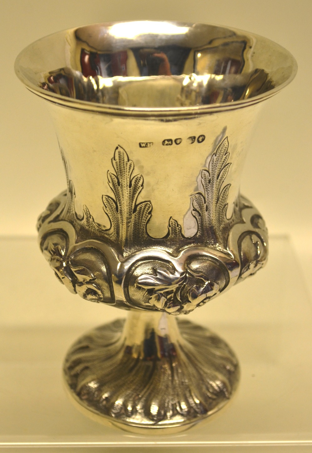 An early Victorian silver goblet, the campana shape body with repouse foliage and stiff leaves, on a