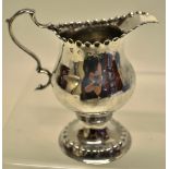 A George III silver inverted pear shape cream jug with a punch beaded rim, a leaf capped scroll