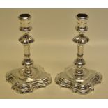 A pair of George II silver cast candlesticks, the girdled campana shape candleholders on moulded
