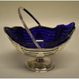 A late Victorian pierced silver navette shape pedestal sugar basket, with a blue glass liner and a