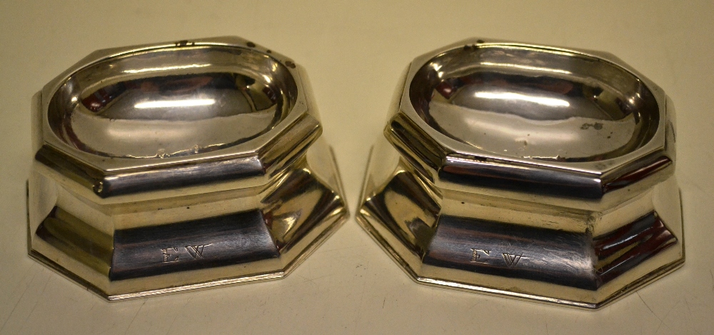 A pair of early George II silver trencher salts, the concave sides with initials EW, angled corners.