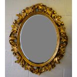 A nineteenth century continental carved gilt wood rococo frame oval mirror, with a bevelled edge