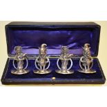 A set of four Edwardian silver novelty menu holders of Mr Punch and Mrs Punch holding baby Punch, on