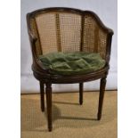 A ladies walnut bergere chair, the channelled frame with carved back panels, ribbon foliage,