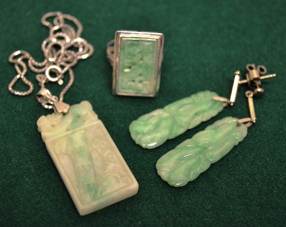 An mottled green jade plaque ring, having rectangular carved and pierced plaque set in white metal