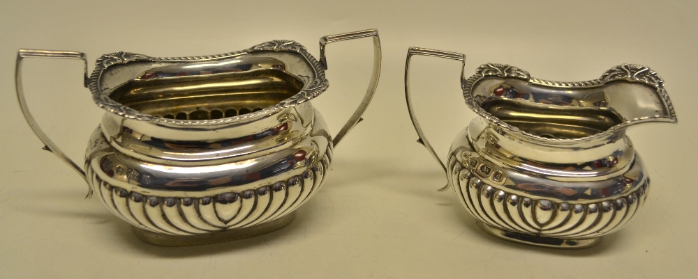 An Edwardian silver sugar and cream set, the partly ribbed ogee rectangular bodies with gadroon