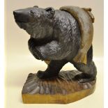 A late nineteenth century black forest carved wood black bear with glass eyes, carrying in a