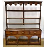 An eighteenth century oak Welsh dresser, the top with arcaded cornice above open plate shelves, iron