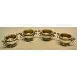 An unusual set of four George III silver salts, the bowls with repousse stiff leaves, with
