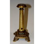 A brass columnar thermometer topped with compass, detailed base and feet,