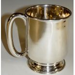 A plain tankard of slightly tapered bellied form on circular stepped foot with plain C-loop handle,
