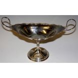 A two handled pedestal dish of shaped oval form, reeded borders and whip-lash handles,