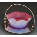 A cranberry opalescent glass dish with frilled rim on silver plated stand, swing handle, 10cm high,